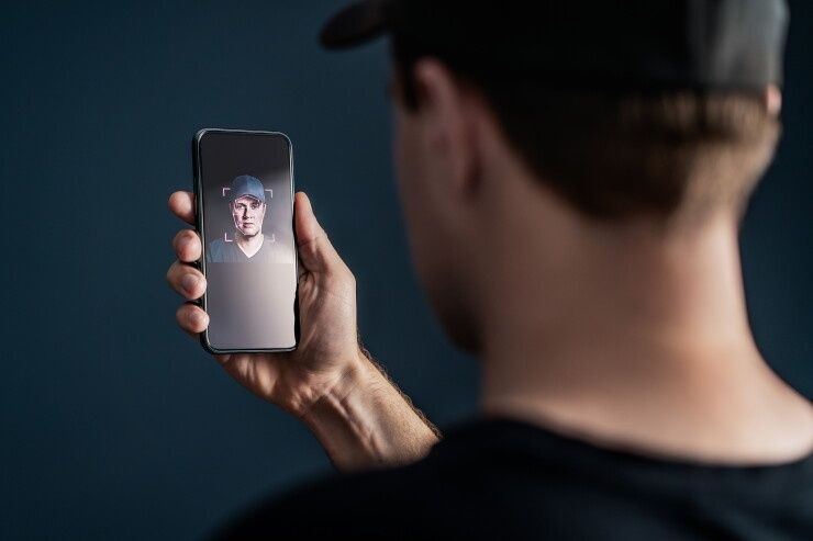 Person håller upp en mobil med ansiktsigenkänning för digital identifiering